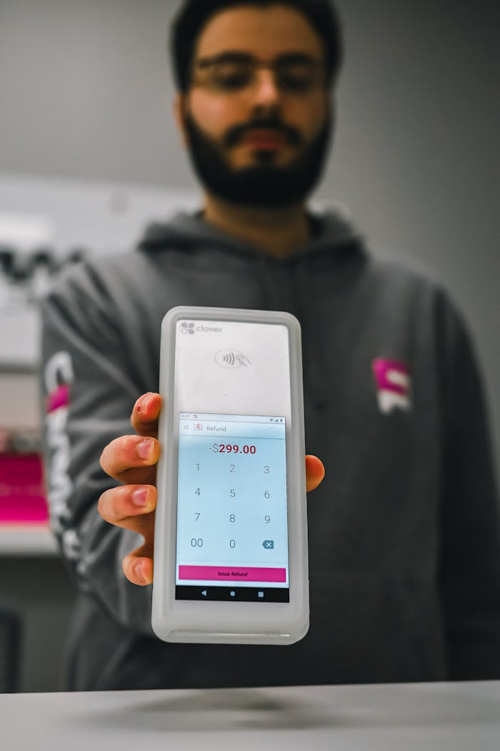 Person displaying touchscreen payment terminal showing $299.00 in a store setting.